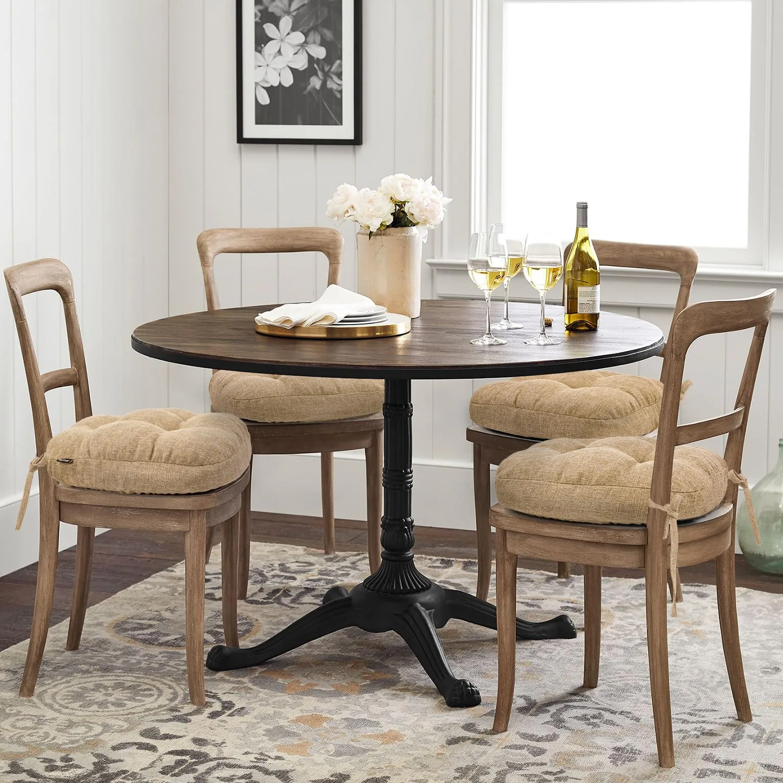 Round dining table set with four wooden chairs fitted with tufted beige seat cushions