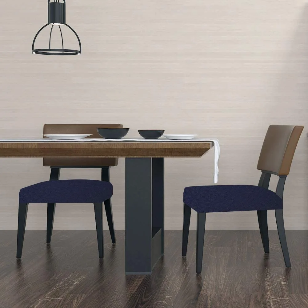 Two dining chairs fitted with navy stretch seat covers beside a wooden table