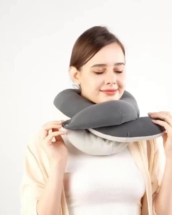 Woman wrapping a grey BUYUE Q-shaped travel neck pillow around her neck and resting her chin on the front support